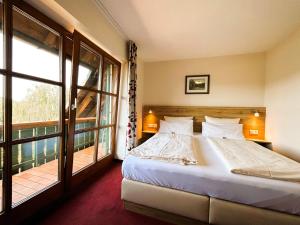 a bedroom with a bed and a large window at Gasthaus und Landhotel Wiedmann in Eresing