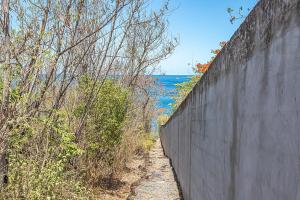 a concrete wall with a path next to the water at Résidence Pommes Cannelles in Bouillante