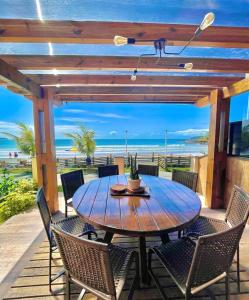 a wooden table and chairs on a patio with the beach at Pousada Vila Del Mare in Bombinhas