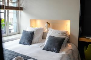 - une chambre avec un lit blanc et des oreillers bleus dans l'établissement Maison d'hôtes du Jardin, à Saint-Valery-sur-Somme