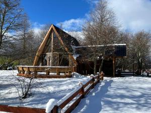 ein Blockhaus im Schnee mit einem Zaun in der Unterkunft CABAÑAS BOSQUE NEVADO in Malalcahuello