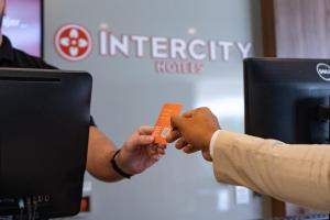 twee mensen wisselen een oranje creditcard uit bij Intercity Montes Claros in Montes Claros