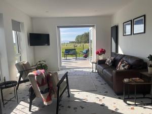a living room with a couch and an open door at Magilligan - Cottage - Sleeps 6 - Parking - Garden in Aghanloo