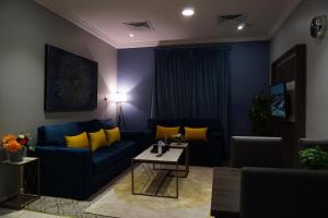 a living room with a blue couch and yellow pillows at Swat Hotel Apartments 2 in Al Khobar