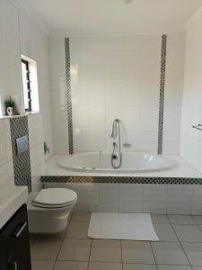 a white bathroom with a tub and a toilet at Olive Exclusive in Gaborone