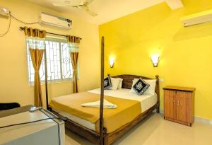 a bedroom with a bed in a yellow room at Santana Guest House in Agonda