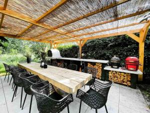 a wooden table and chairs under a wooden pergola at VILLA CALMA Rust Ruimte Luxe inclusief private jacuzzi in Zeewolde