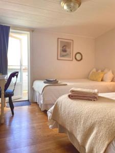 a bedroom with two beds and a desk and a window at Hotell & Restaurant Solliden in Stenungsund