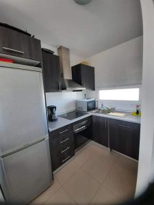 eine Küche mit schwarzen Schränken und einem weißen Kühlschrank in der Unterkunft casa paradisiaca in Murcia