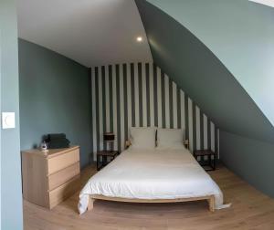 una camera con un letto bianco e una parete a righe di Appartement centre - La Gacilly a La Gacilly
