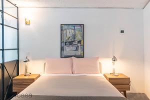 ein Schlafzimmer mit einem großen Bett mit zwei Nachttischen in der Unterkunft Comfortable Apt. w/ Terrace & Lovely Lighting 101 in Mexiko-Stadt