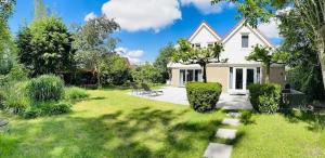 Cette grande maison blanche dispose d'une cour avec une pelouse. dans l'établissement VILLA CALMA Rust Ruimte Luxe inclusief private jacuzzi, à Zeewolde