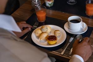 einen Tisch mit einem Teller Essen und einer Tasse Kaffee in der Unterkunft Intercity Montes Claros in Montes Claros