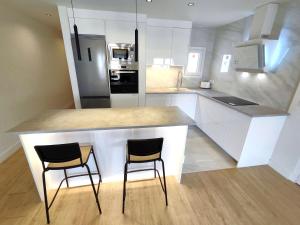 uma cozinha com um balcão e duas cadeiras numa ilha de cozinha em Puertollano Central Park - by Pro Apartments em Puertollano