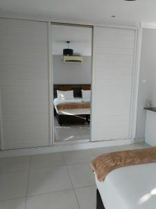 a bedroom with white blinds and a bed with a mirror at Olive Exclusive in Gaborone