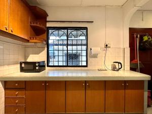 a kitchen with a counter and a window at BNB Cozy Homestay @ Bdr Country Homes (Corner Hse) in Rawang