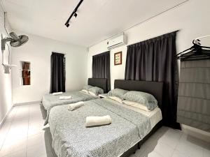 a bedroom with two beds with towels on them at BNB Cozy Homestay @ Bdr Country Homes (Corner Hse) in Rawang