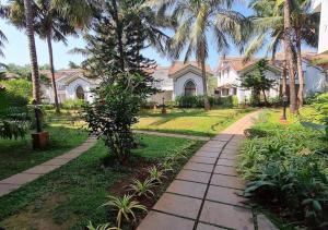 a walkway in front of a house with palm trees at Riviera Hermitage Goa in Arpora