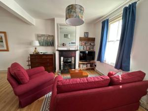 a living room with two red couches and a fireplace at Beautiful Victorian house in central Cambridge in Cambridge