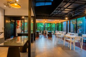 ein Restaurant mit weißen Tischen, Stühlen und Fenstern in der Unterkunft Colorful Pool Villa in Ban Chin Tham Mai