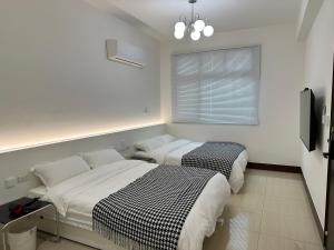 two beds in a white room with a window at 金門且停民宿 可包棟 好停車 近市區 in Jinning