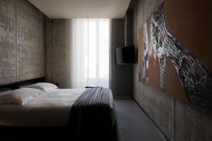 um quarto com uma cama, uma televisão e uma janela em STRAF, Milan, a Member of Design Hotels em Milão