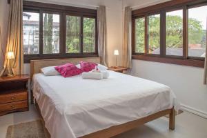 um quarto com uma grande cama branca com almofadas cor-de-rosa em LOCAR-IN GRAMADO - Loft a 50 m da Rua Coberta em Gramado