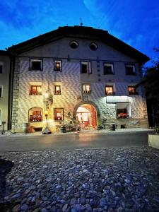 un grande edificio in pietra con facciata illuminata di Chasa de Capol - Historische Gaststätte & Weinkellerei a Santa Maria Val Müstair