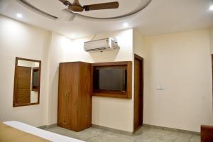 a room with a tv and a wall with a fan at HOTEL AROMA CROWN in Zirakpur