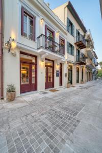 ein großes weißes Gebäude mit roten Türen und Fenstern in der Unterkunft Isioni Pension in Nafplio