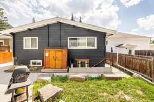 a black house with a fence in front of it at Cougar Street Mountain Rental in Banff