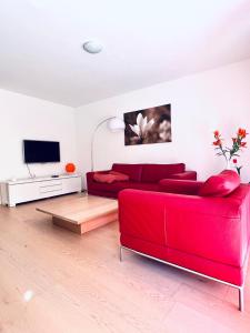 FlumserbergにあるFerienwohnung Arvenstrasse - CharmingStayのリビングルーム(赤いソファ、テレビ付)