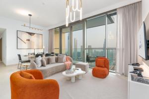 a living room with a couch and orange chairs at Ultimate Stay Full Burj Khalifa & Downtown Views Designer Luxury High Floor for 6 People in Dubai
