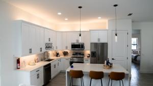 a kitchen with white cabinets and a kitchen island with chairs at Corallo House - Heated Pool in Cape Coral