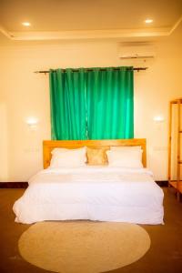 a bedroom with a large bed with a green curtain at PALM CULTURAL VILLAGE in Paje