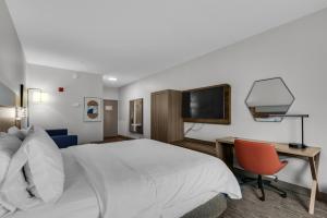 ein Hotelzimmer mit einem Bett, einem Schreibtisch und einem TV in der Unterkunft Holiday Inn Express Destin E - Commons Mall Area, an IHG Hotel in Destin