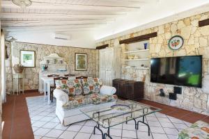 a living room with a couch and a tv on a stone wall at Villa del Mito in Plemmirio