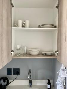 a kitchen sink with plates and dishes on shelves at Cosy Studio with Spectacular Views in Cape Town