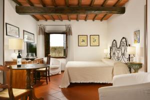 Romantik Hotel Monteriggioni في مونتيريجيوني: غرفة نوم بسرير وطاولة وكراسي