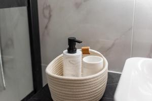 uma cesta com uma garrafa de sabão e papel higiénico em Appartement moderne à 2 pas de la Gare em Toulouse