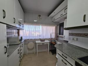 een keuken met witte kasten en een tafel en een raam bij Apartamento Edificio Santa Margarita in Benidorm