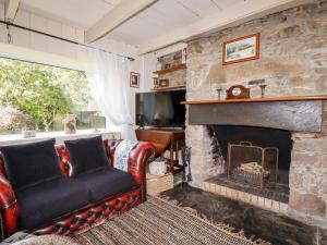 a living room with a stone fireplace and a couch at Quiet Trees in Bodmin