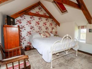 a bedroom with a white bed with red floral wallpaper at Quiet Trees in Bodmin