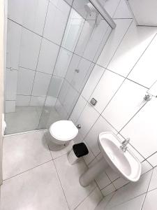 a white bathroom with a toilet and a sink at Poupahotel in Taubaté