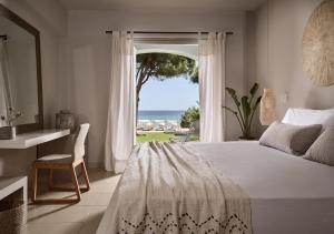 a bedroom with a bed and a view of the ocean at The Bay Hotel & Suites in Vasilikos