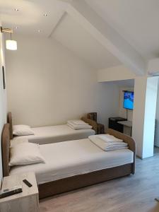 three beds in a room with a tv at UB Prenociste in Vranjska Banja