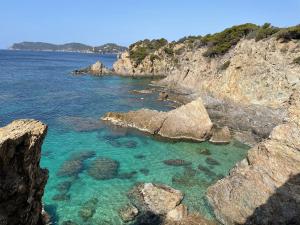 una orilla rocosa con agua azul y rocas en Loft T3 Duplex Vue Mer Porquerolles, en Hyères