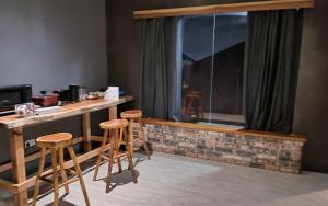 une chambre avec un bureau et deux tabourets devant une fenêtre dans l'établissement The Manzonia, à Tema