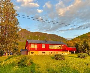 a red house in a field with mountains in the background at Lofoten Red Villa in Laupstad