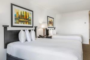 two beds in a hotel room with white pillows at The Ridge Hotel in Lake Geneva